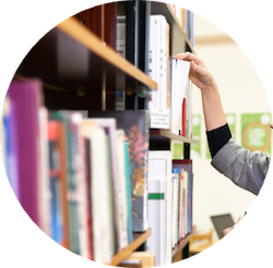 Library shelf full of books. Hand grabbing a book off a shelf