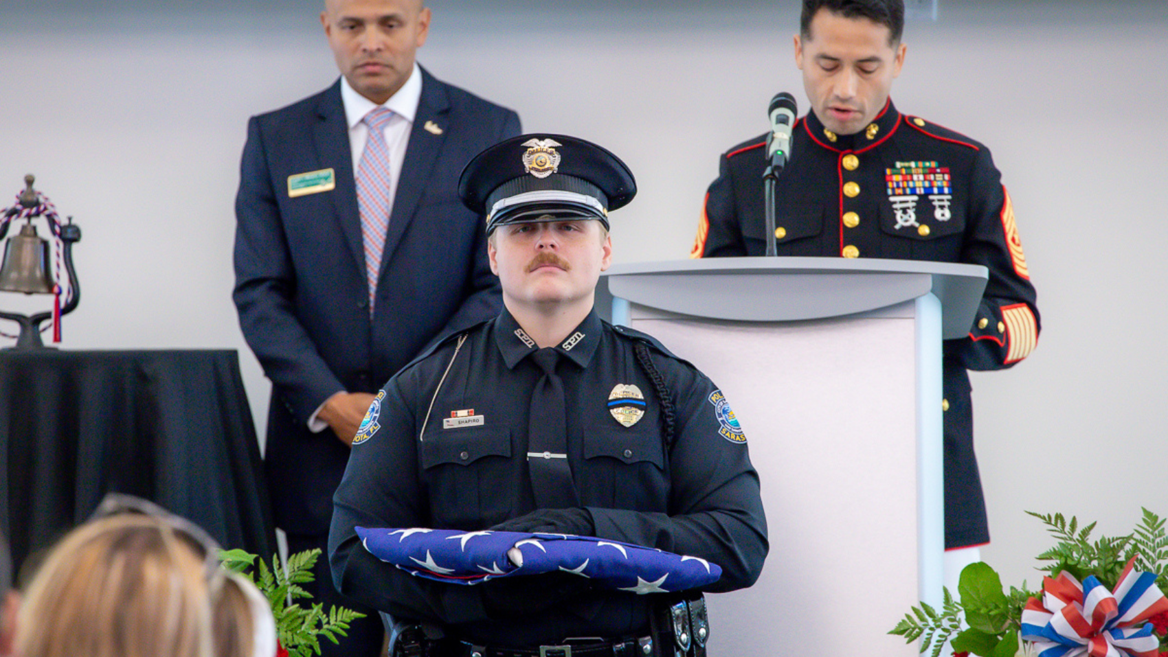 sarasota police officer holding folded flag looking straight