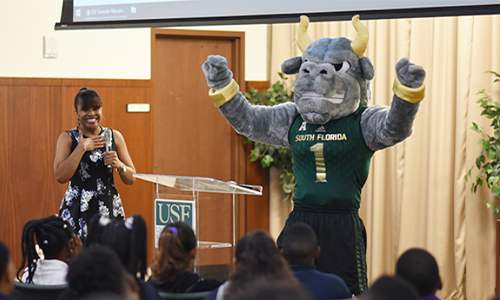 Rocky raising his hands above his head in front of fifth graders.