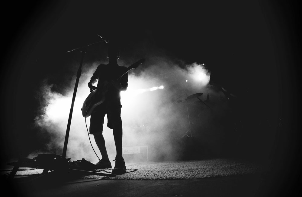 Guitarist in on stage in spotlight of mist.