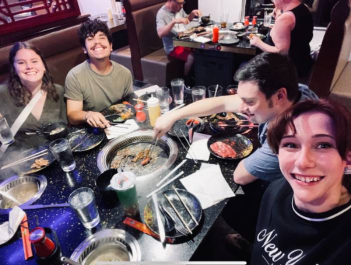 Elyssa with friends smiling, enjoying food.