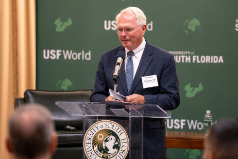 Ambassaor Christopher Hill speaking at the podium with USF logo