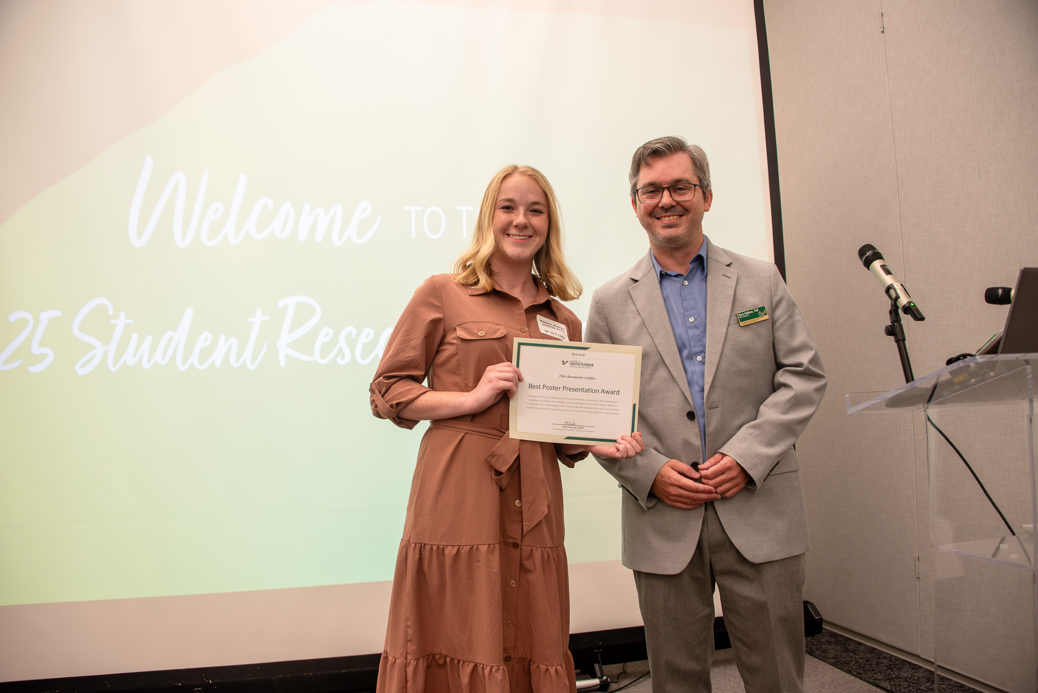 Student holding up award for Best Student Presentation standing next to Ross DuBose, PhD