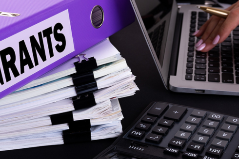 image of someone touching a computer keyboard with grant papers