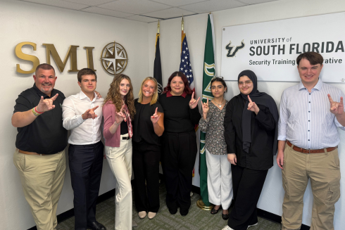 Security Training Collaborative Interns give the Bulls hand sign while smiling at the camera