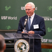 Ambassaor Christopher Hill speaking at the podium with USF logo